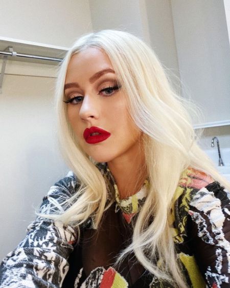 Christina Aguilera in a black top poses for a picture.
